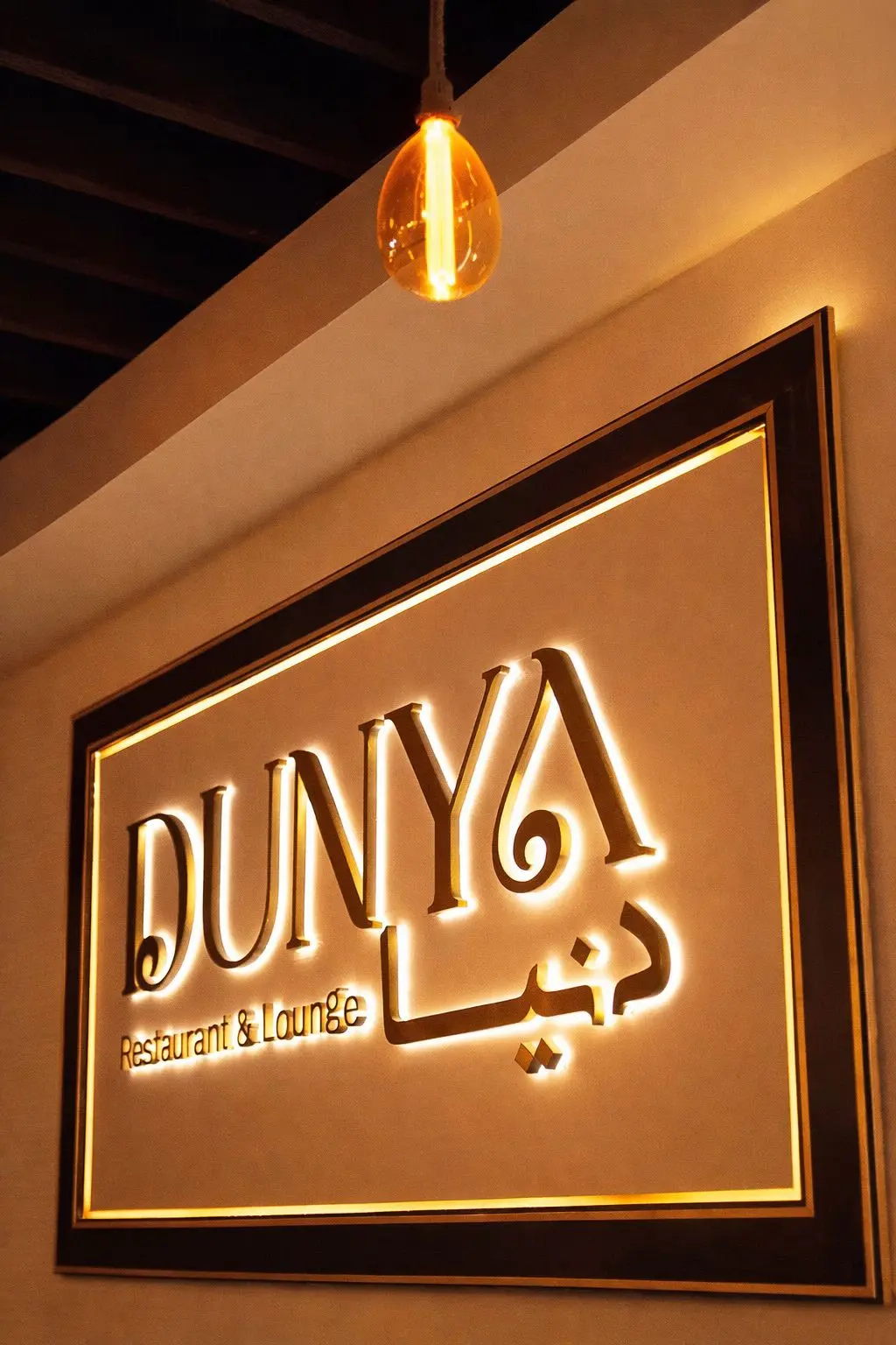 Dunya Lounge gold-framed illuminated sign at the entrance on Fifth Avenue
